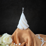 White twisted pillar candle from The Twirl Pillar Candle Collection displayed on beige satin cloth with white roses and pearl necklace.