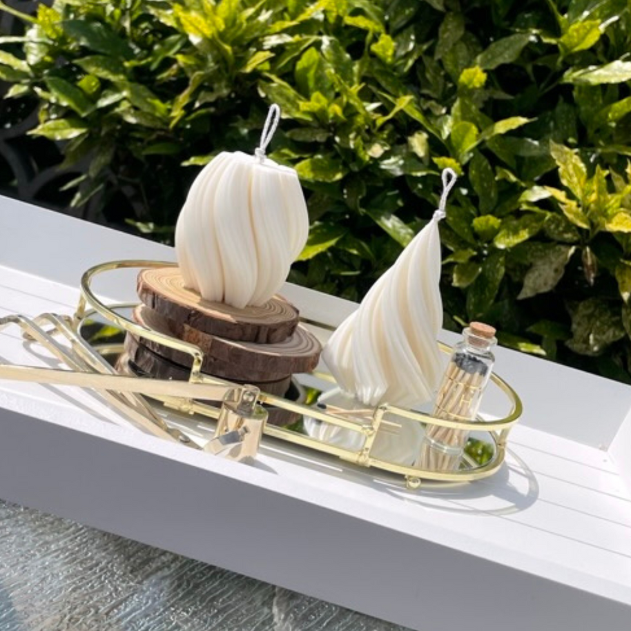 Elegant white twisted pillar candles from The Twirl collection displayed on a gold tray outdoors