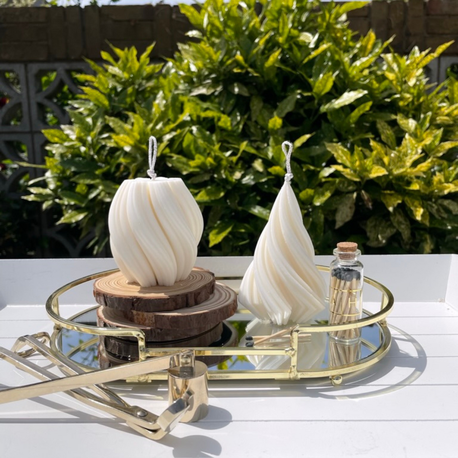 Hand poured soy blend pillar candles from The Twirl collection displayed on wooden slices and mirrored tray, featuring natural cotton wicks and elegant swirl designs