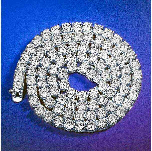 Gold 3 mm CZ Tennis Chain with sparkling cubic zirconia stones on gold-tone brass setting coiled on blue background