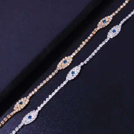 Two vintage evil eye crystal anklets with cubic zirconia stones in silver and gold finishes on black background