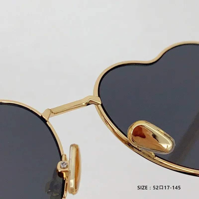 Close-up of Heart a luv sunglasses with gold acetate frames and black photochromic lenses, UV400 protected.