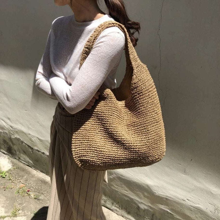 Casual summer shoulder beach bag made of soft straw with a roomy interior and bohemian style design
