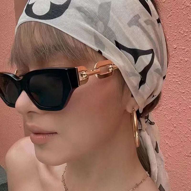 Fashion Cat Eye Sunglasses with black frames and gold accents worn by woman with headscarf and hoop earrings