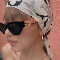 Fashion Cat Eye Sunglasses with black frames and gold accents worn by woman with headscarf and hoop earrings