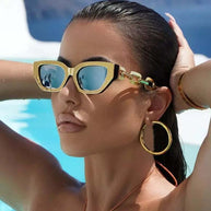 Fashion cat eye sunglasses with gold frame and blue mirror lenses worn by woman by pool