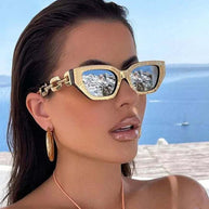 Fashion cat eye sunglasses with gold frame and mirrored lenses worn by woman near water background