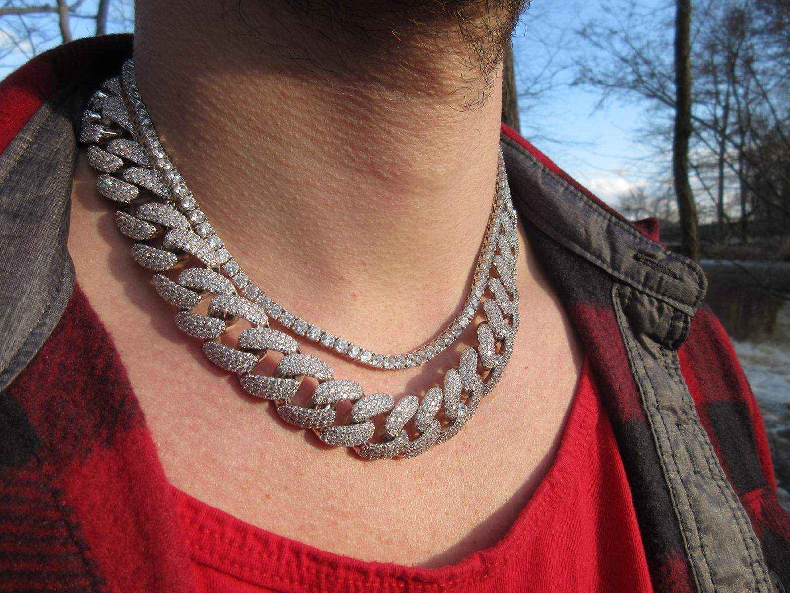 Stallion Iced 18 mm Cuban Chain with sparkling cubic zirconia on a person wearing a red shirt and jacket outdoors