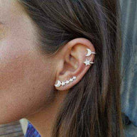 Close-up of ear wearing a Moon - Star Earring and cuff set with gold-tone celestial designs and crystal accents.