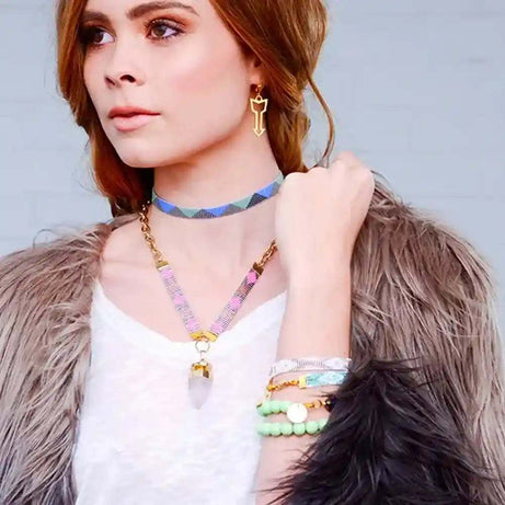 Woman wearing St. Tropez Blue Quartz Necklace with chunky crystal quartz pendant on 24K gold-plated chain and colorful hand-woven bead strap.