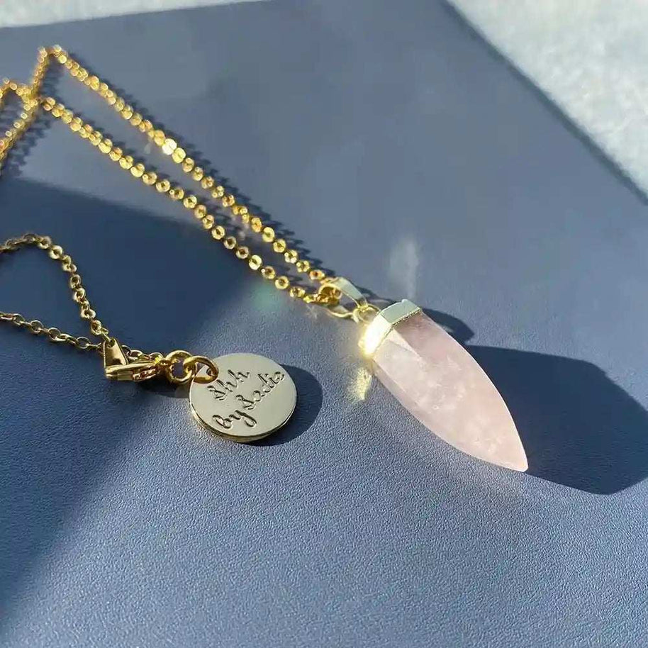 Gold-plated Glow Crystal Quartz Necklace with rose quartz pendant and signature Shh by Sadie tag on chain