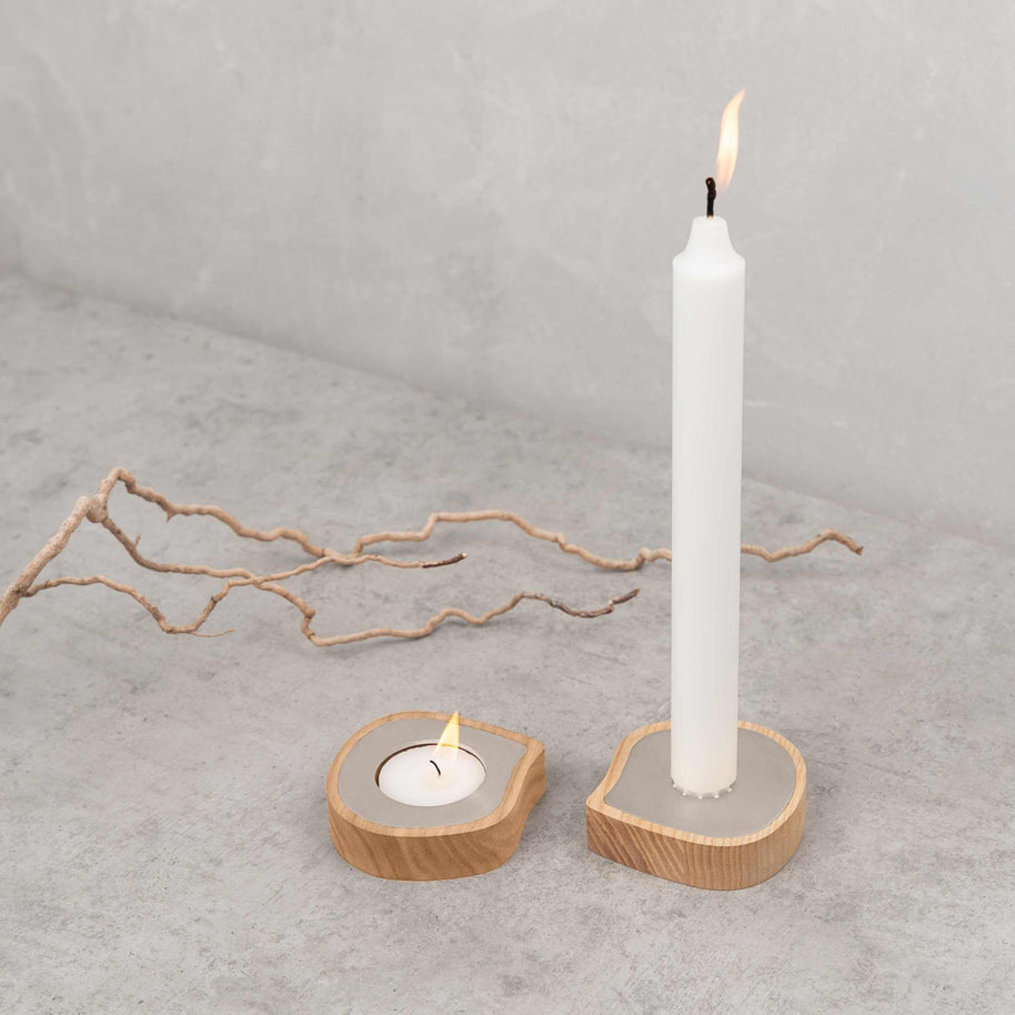 Ash wood taper candle holder and tealight holder with stainless steel detail on concrete surface