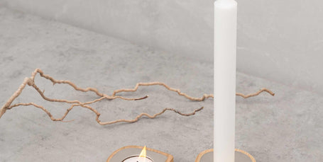 Ash wood taper candle holder and tealight holder with stainless steel detail on concrete surface