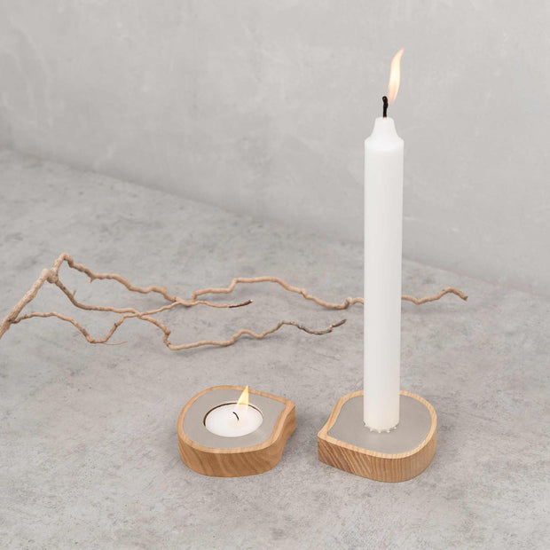 Ash wood taper candle holder and tealight holder with stainless steel detail on concrete surface