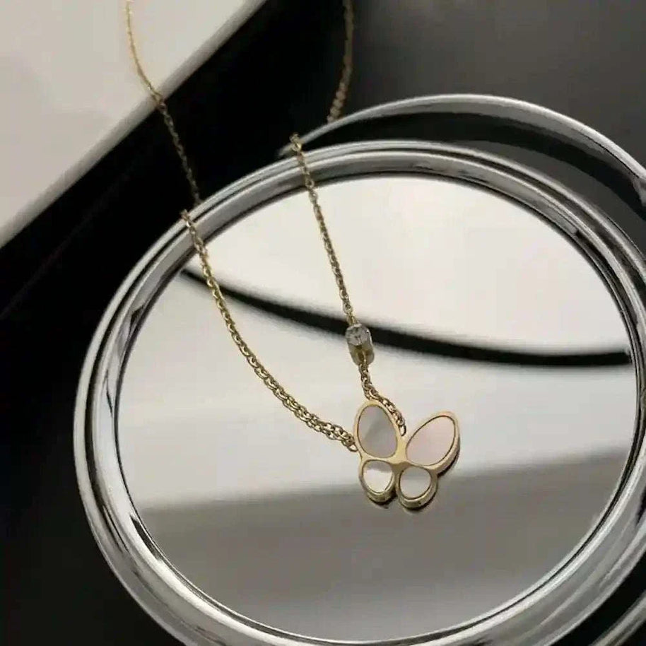 Butterfly Mother-of-Pearl Necklace with gold-plated chain and iridescent butterfly pendant on reflective surface