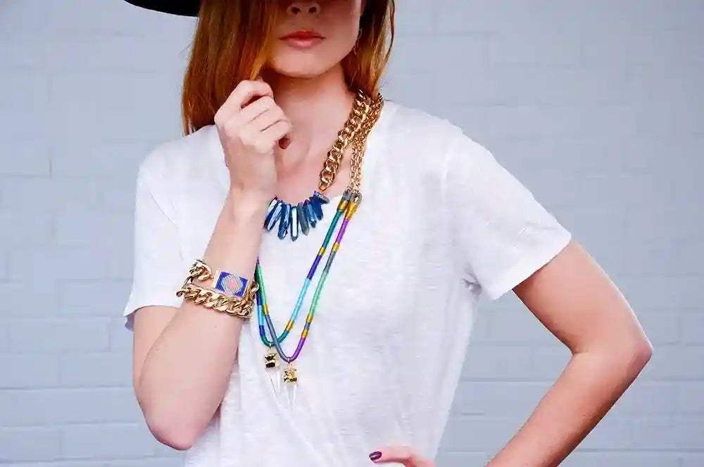 Chunky Classic Chain Bracelet in gold-tone worn on wrist with layered necklaces and white shirt