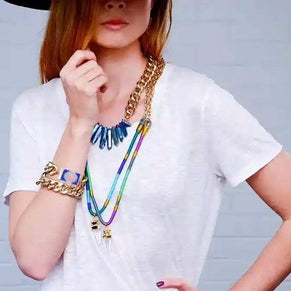 Chunky Classic Chain Bracelet in gold-tone worn on wrist with layered necklaces and white shirt