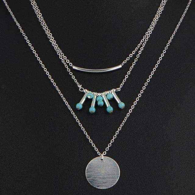 Turquoise layered necklace with silver chains and turquoise beads on black background