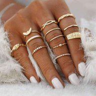 Hand wearing 12-piece Golden Gem Stackable Rings set in various gold designs with gemstone accents on all fingers