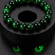 Dark bottle green bead bracelet with polished round beads on a black display against a dark background.