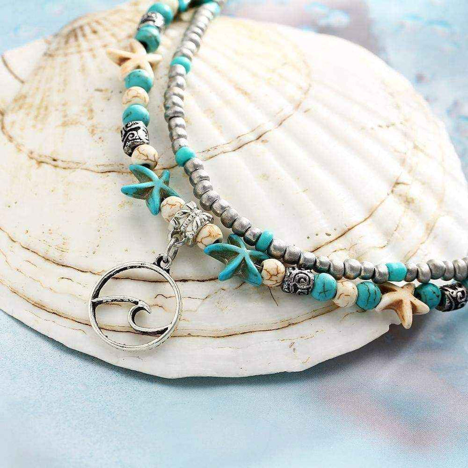 Ocean Double Layer Anklet with turquoise beads, starfish charms, and ocean wave pendant on seashell background