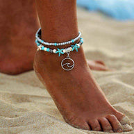 Ocean Double Layer Anklet with turquoise beads and ocean wave charm on sandy beach foot