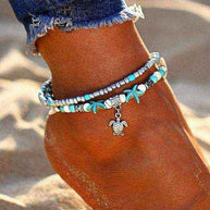 Ocean Double Layer Anklet with turquoise beads and turtle charm on ankle in beach sand