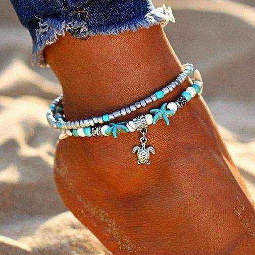 Ocean Double Layer Anklet with turquoise beads and turtle charm on ankle in beach sand
